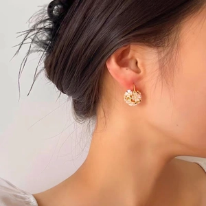 Elegante goldene Blumenkorb-Ohrringe mit rosa Blüten und grünen Kristallen am Model