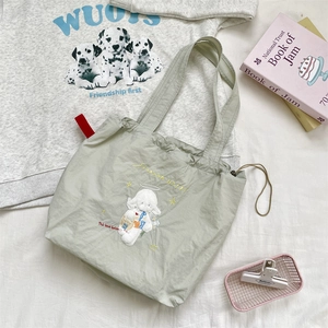 Detail of sage green nylon tote bag with cute cartoon sheep embroidery and red side label
