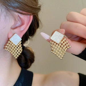 Detailed macro view of woven diamond gold earrings with elegant white marble finish