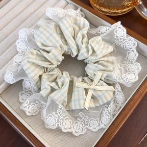 Detail of yellow and green plaid scrunchie with white lace floral trim and bow