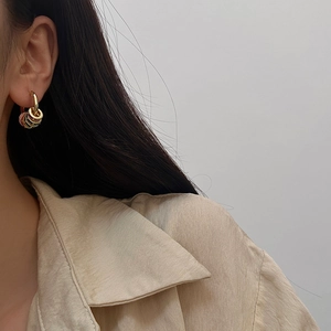 Close-up of a woman wearing gold hoop earrings with colorful dangling rings in retro style