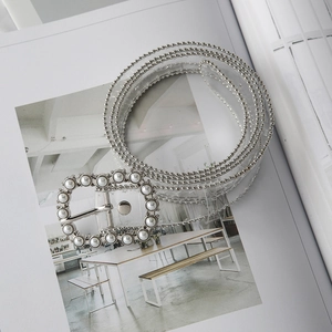 Detail view of transparent PVC belt with silver bead trim and pearl-encrusted buckle