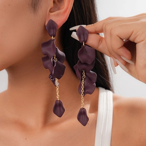 Detail of dark purple acrylic petal tassel earrings with golden chains on model