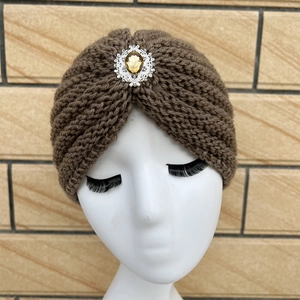 Detail of brown knitted headband with sparkling amber gemstone brooch for women