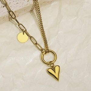 Detailed macro shot of gold double-layer necklace with heart pendant and paperclip chain