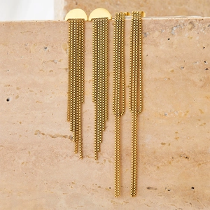 Elegant long gold tassel earrings in stainless steel displayed on a natural beige stone