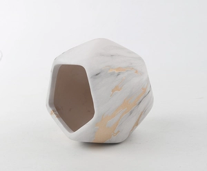 Detail of geometric marble pattern ceramic planter with gold accents and bamboo tray