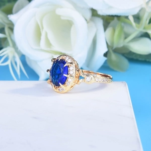 Macro shot of luxury royal blue sapphire ring with gold plating on marble surface