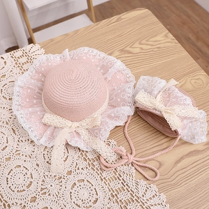 Flat lay of pink straw sun hat and matching bag set with delicate lace bow details