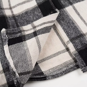 Close-up van de zwart-witte geruite wollen jas met stoftextuur en knoopdetails