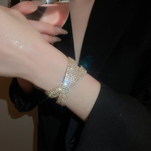 Détail d'un bracelet croisé doré serti de zircons brillants porté par un mannequin
