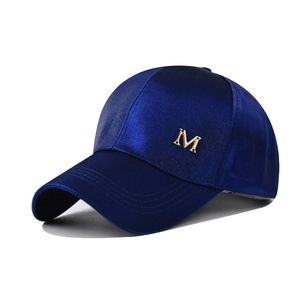 Vue détaillée d'une casquette en satin bleu foncé avec logo métallique M doré poli