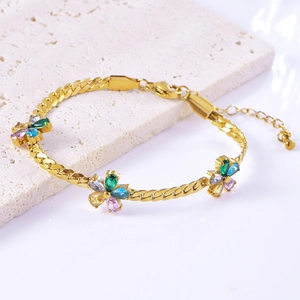 Detailed shot of golden flower bracelet with multicolor zircon stones on stone surface