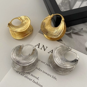 Detailed view of gold and silver metallic earrings with layered rippled texture design