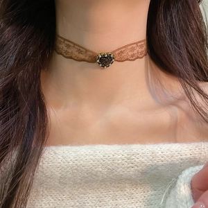 Detail of vintage brown lace choker with heart pendant and pearls on model neck