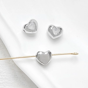 Macro detail of 18k gold plated heart spacer beads with silver finish for DIY jewelry