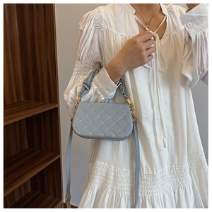 Detail of light blue quilted crossbody bag with gold floral rivets and handle