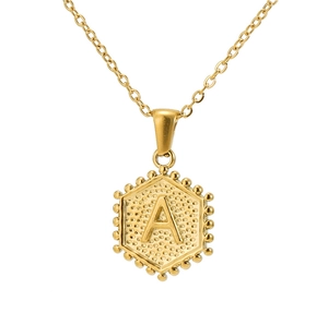 Detailed view of an 18K gold hexagon pendant with letter A engraving and beaded edges