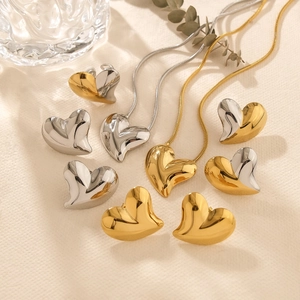 Elegant gold and silver heart necklace and earring set on a minimalist textured surface