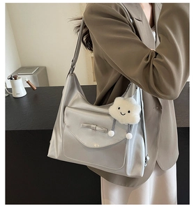 Detail of silver tote bag with bow accent and cute cloud plush charm on shoulder strap