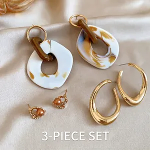 Three-piece set of vintage pearl fish-tail earrings and resin hoops on silk
