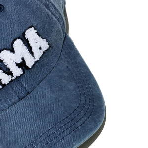 Detailed close-up of white chenille MAMA letter patch on washed blue cotton baseball cap