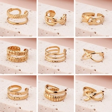 Collection of nine gold-plated stainless steel adjustable rings on white stone bases