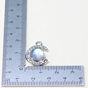 Silver crescent moon pendant with blue iridescent gem and white crystal accents