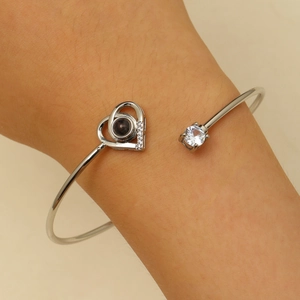 Détail d'un bracelet coeur argenté avec une pierre de projection je t'aime en 100 langues