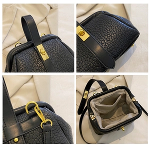 Detail view of black textured leather handbag with gold hardware and interior compartments