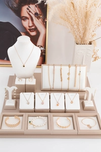 Professional jewelry display set with gold necklaces, rings, and beige display stands