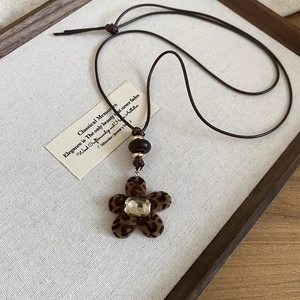 Close-up of leopard print flocked flower pendant with square diamond and brown cord