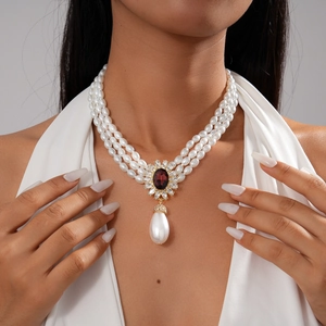 Gros plan d'un collier de perles à trois rangs avec pendentif fleur rouge sur mannequin
