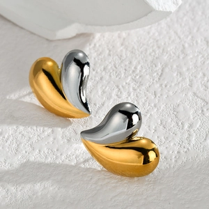 Macro view of bicolor heart stud earrings with polished gold and silver finish