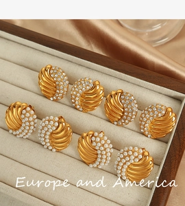 Detailed close-up of golden spiral earrings with pearls and crystals in a velvet tray