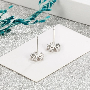Elegant silver five-petal flower stud earrings on white card with blue floral decor
