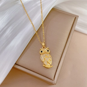 Detailed shot of a gold owl necklace with sparkling crystals on white silk background