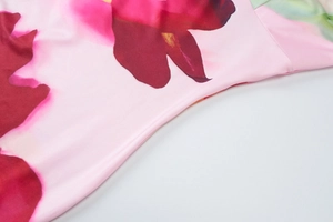 Detail of pink floral print on smooth satin fabric with rose patterns on backless dress