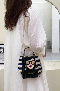 Detail of square box bag with cartoon portrait, gold chain and silk scarf handle wrap