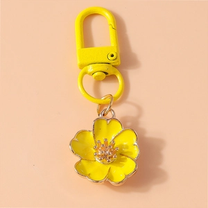 Detailed view of yellow flower keychain pendant with polished metal and lacquer finish