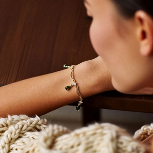 Nahaufnahme des 18k vergoldeten Armbands mit grünem Wassertropfen-Anhänger am Handgelenk