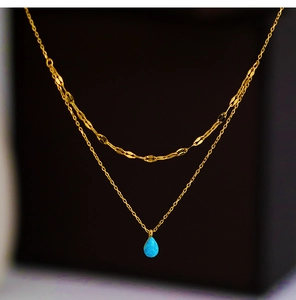 Detail of double-layer gold chain necklace with light blue teardrop opal pendant