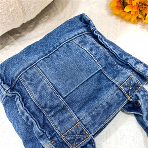Detailed close-up of dark blue denim handbag featuring contrast orange stitching