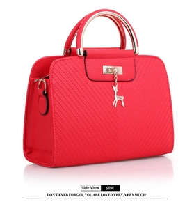 Detail view of red embossed leather handbag with golden lock and deer charm