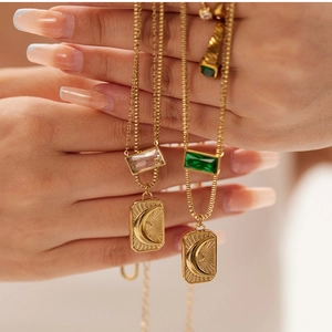 Detail of layered gold necklace with moon sun engraved charms and rectangular gems