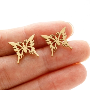 Golden stainless steel butterfly stud earrings with hollow design shown on finger