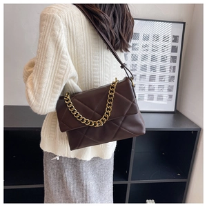Detail van donkerbruine crossbodytas met gewatteerde textuur en gouden grove ketting