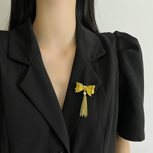 Detail of vintage gold bow brooch with metal tassels and pearl on a blazer lapel