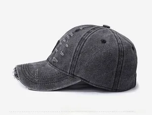 Detail view of distressed charcoal grey washed denim baseball cap with torn fabric texture
