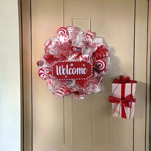 Red and white Christmas peppermint wreath with Welcome sign on a beige front door